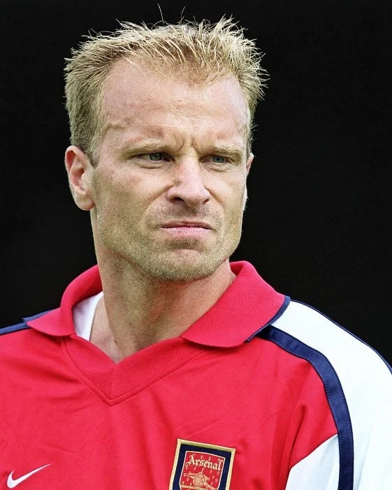 Dennis Bergkamp in een rood Arsenal voetbalshirt tijdens een wedstrijd.