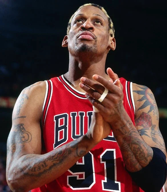 Dennis Rodman in een rood Chicago Bulls nummer 91 basketbalshirt met zichtbare tatoeages.