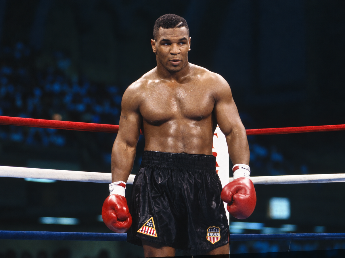 Mike Tyson in de boksring met rode bokshandschoenen en zwarte boksshort.