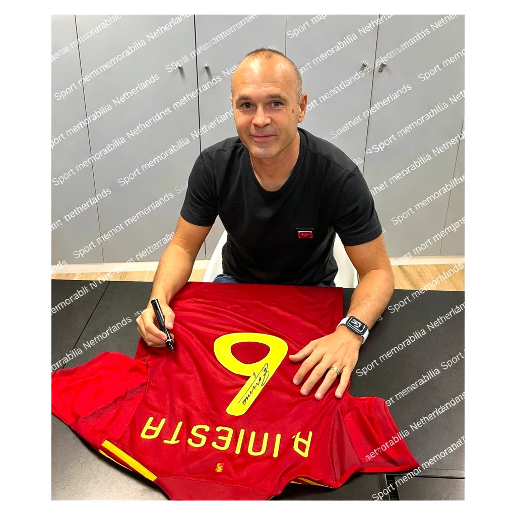 Foto van Andrés Iniesta tijdens het signeren van een Spanje voetbalshirt. Authentiek gesigneerd memorabilia met certificaat – Sport Memorabilia Netherlands.