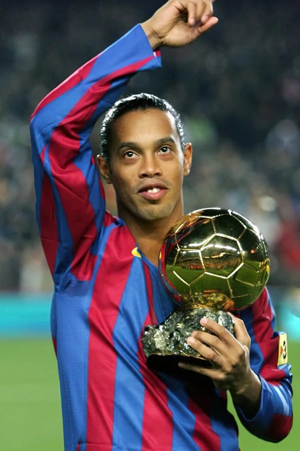 FC Barcelona football player holding the Ballon d'Or trophy during a celebration on the pitch.