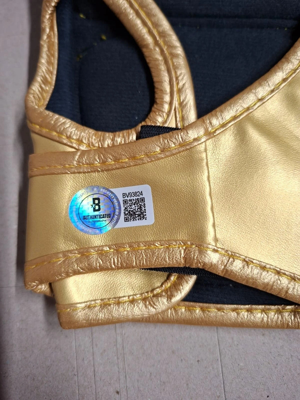 Detail van de Beckett-authenticiteitssticker op de gouden UFC-handschoen van Conor McGregor.
