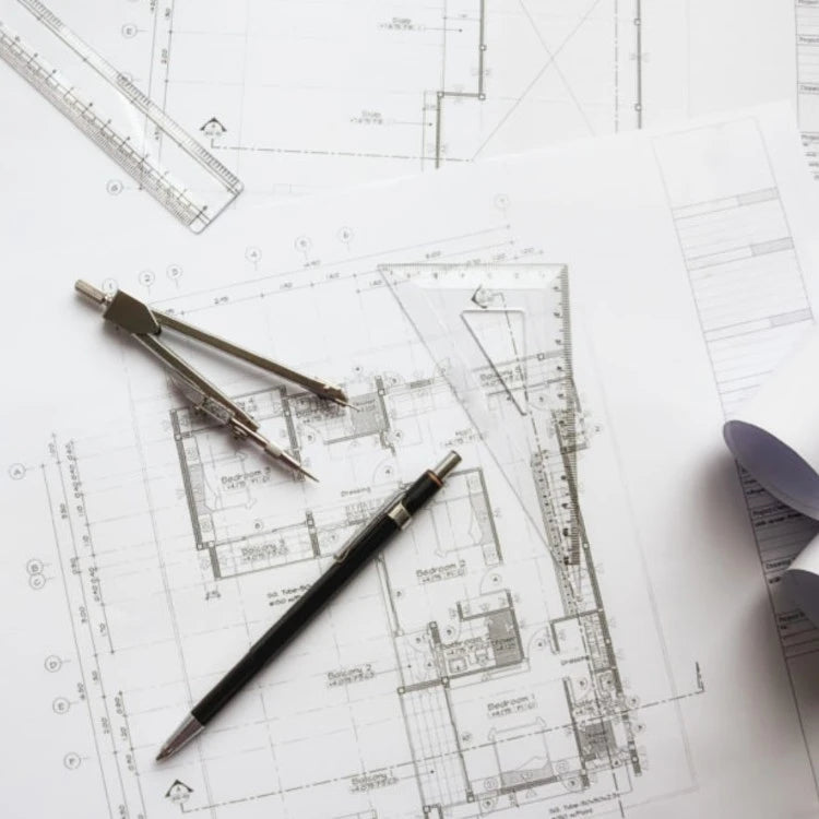 Architectural plans with measuring tools representing a professional custom framing service.