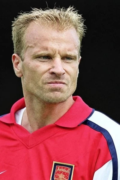 Dennis Bergkamp in een rood Arsenal voetbalshirt tijdens een wedstrijd.