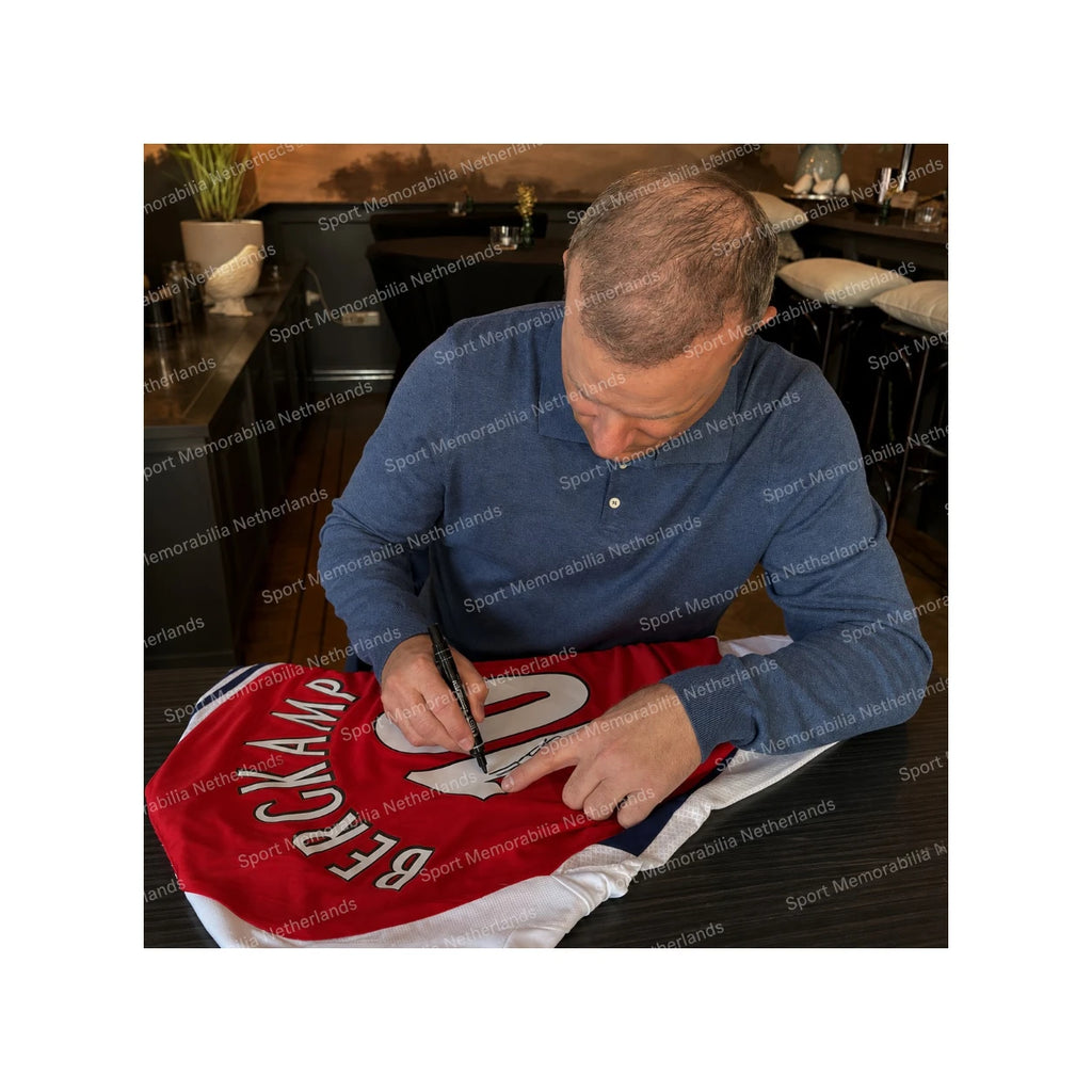 Dennis Bergkamp signing an official Arsenal 2024-25 home football shirt during a private signing session.