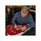 Dennis Bergkamp signing an official Arsenal 2024-25 home football shirt during a private signing session.