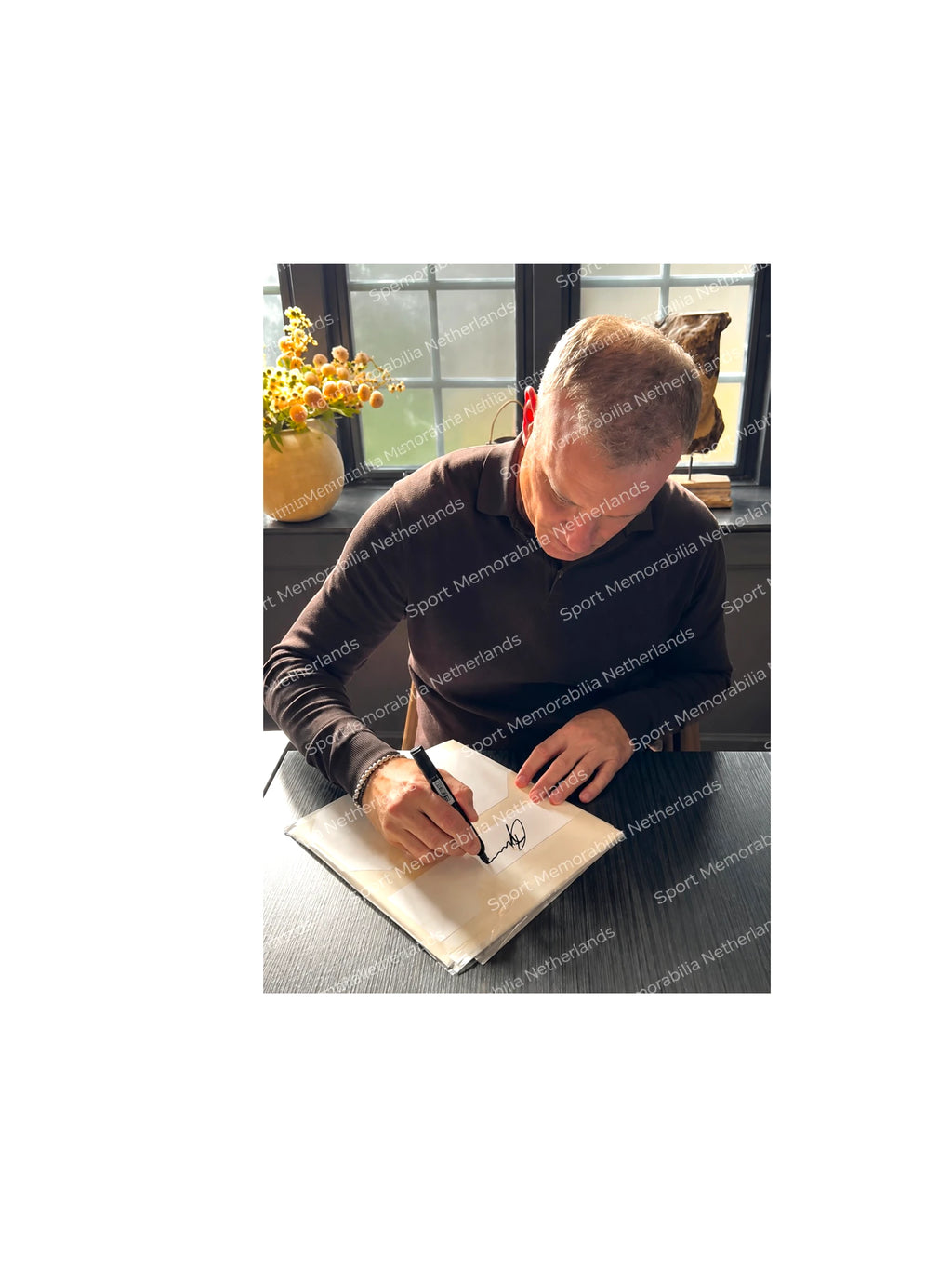 Dennis Bergkamp signing an official replica Holland 1994 home football shirt during a private signing session.