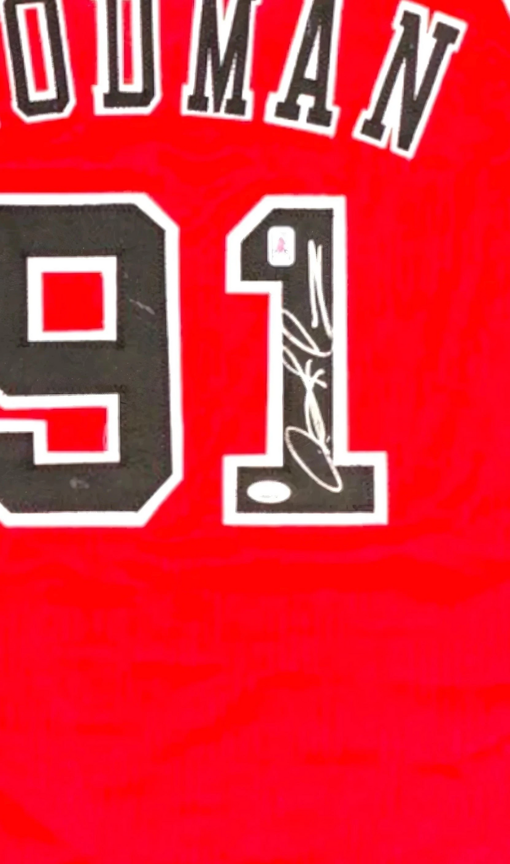 Detail van de handtekening van Dennis Rodman op nummer 91 van een rood basketbalshirt.