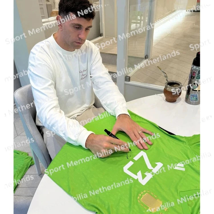 Signing proof of Emiliano Martínez signing a green Argentina goalkeeper shirt during a private signing session.