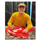 Eric Cantona tijdens het signeren van een rood Manchester United nummer 7 voetbalshirt.