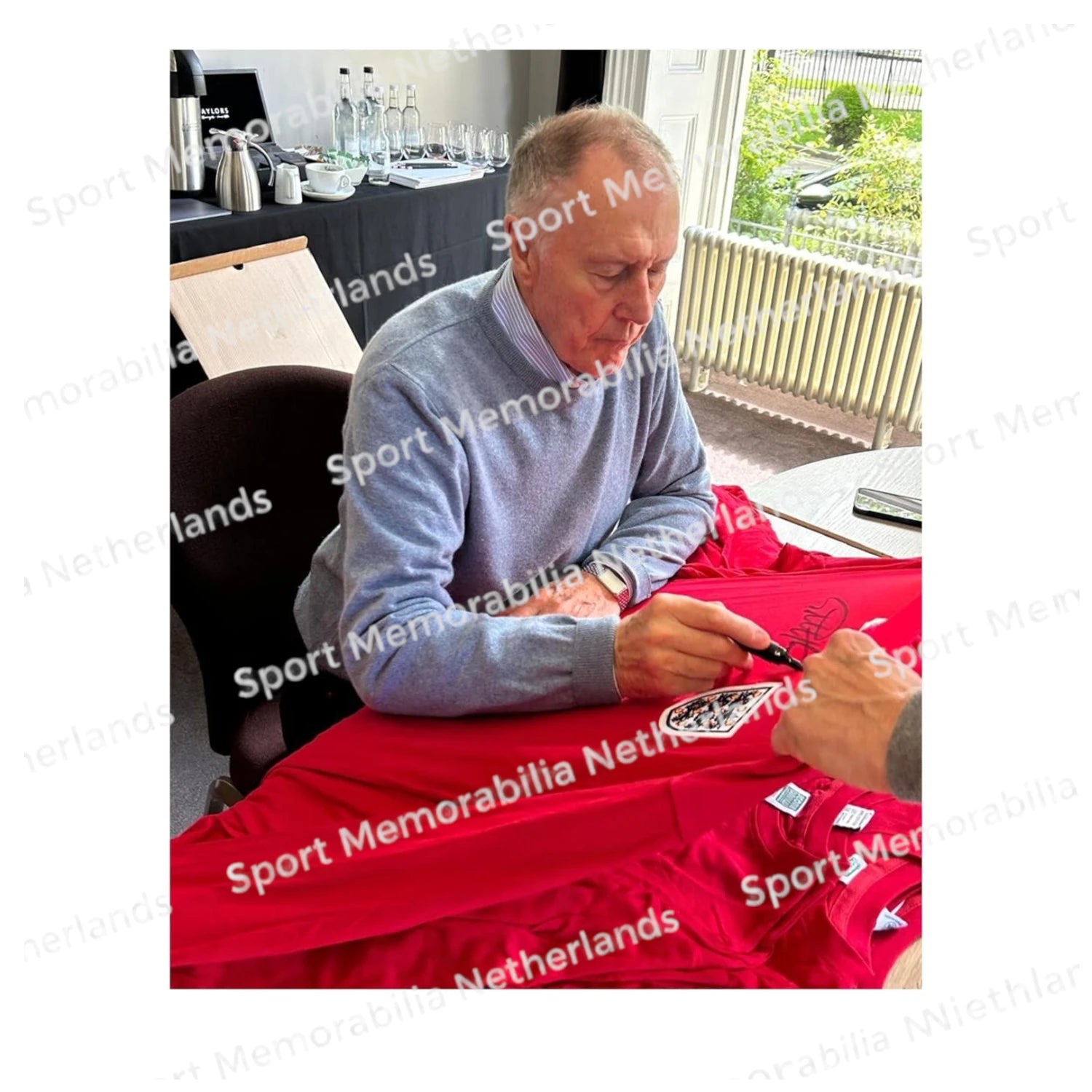 Signing proof of Geoff Hurst signing an official England football shirt during a private signing session.