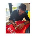 Gianluigi Buffon signeert een rood Juventus keepersshirt met rugnummer 1 tijdens een signeersessie. De handtekening wordt op het witte rugnummer geplaatst.