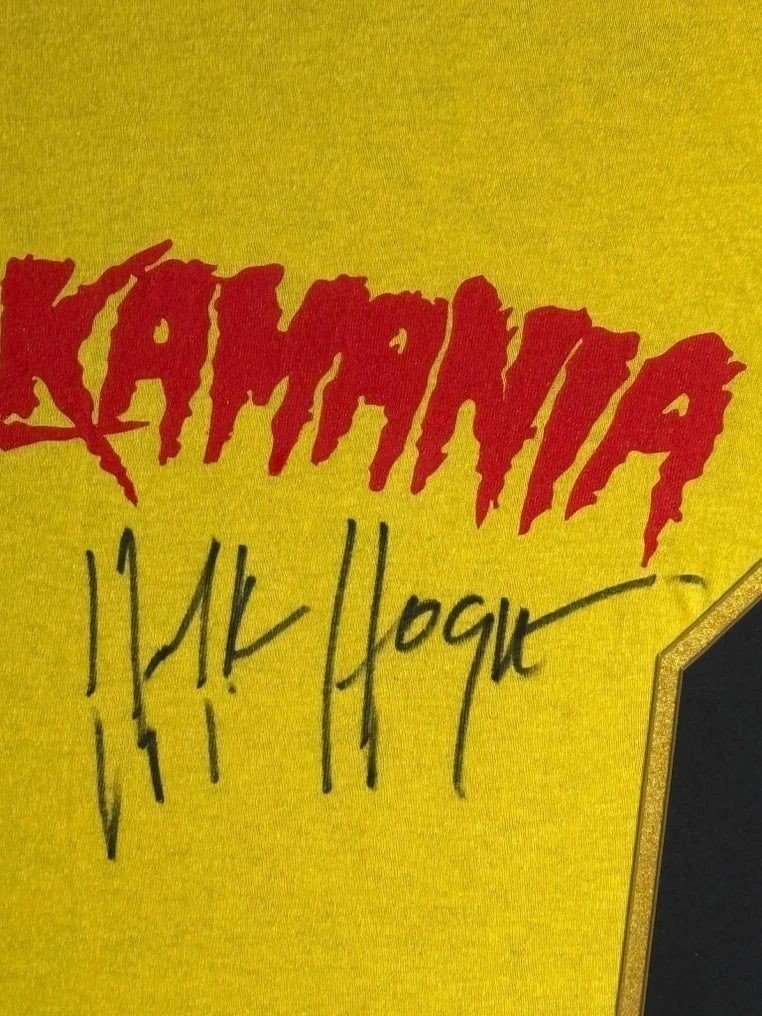 Detail van de handtekening van Hulk Hogan op een geel Hulkamania-shirt.