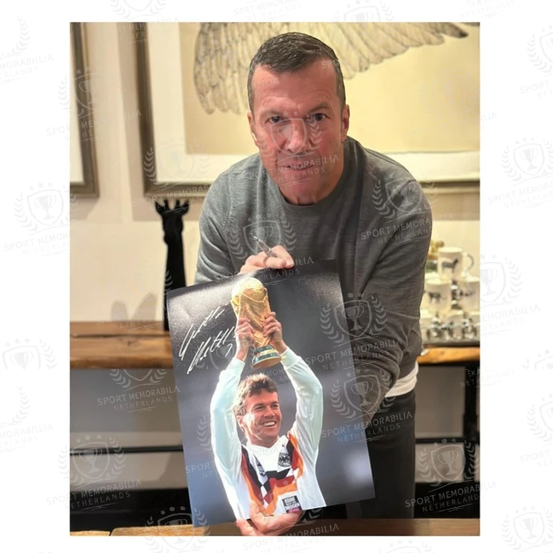 Lothar Matthäus tijdens het signeren van een Duitsland WK-voetbalfoto met de wereldbeker.