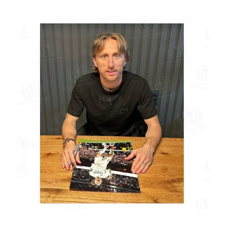 Luka Modrić tijdens een signeermoment met een gesigneerde Real Madrid voetbalfoto