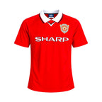 Voorkant van een klassiek rood Manchester United voetbalshirt van Umbro met witte kraag, zwarte details, SHARP-sponsor en Manchester United-clublogo.
