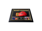 Schuin bovenaanzicht van een liggend Deluxe Frame met rode Everlast bokshandschoen gesigneerd door Manny Pacquiao, zwart-gouden lijst en twee boksfoto's.