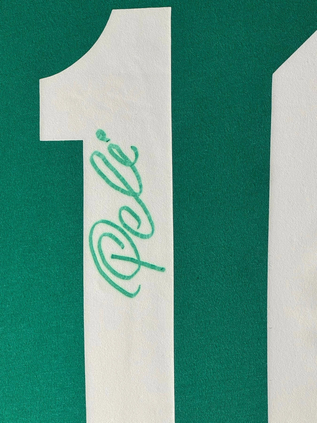 Detailfoto van de handtekening van Pelé op het witte rugnummer 10 van een groen voetbalshirt.