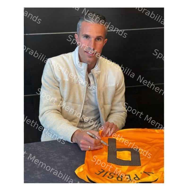 Robin van Persie tijdens het signeren van een oranje Nederland nummer 9 voetbalshirt.