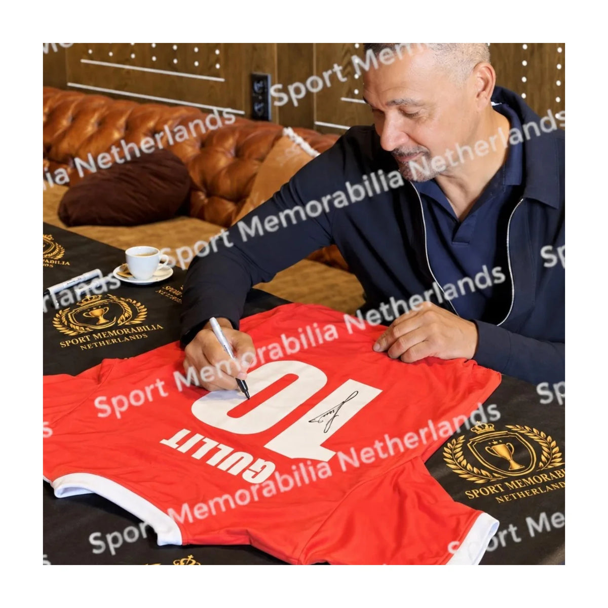 Ruud Gullit tijdens het signeren van een rood PSV 1986 replica voetbalshirt met nummer 10.