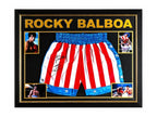 Framed Rocky Balboa boxing shorts signed by Sylvester Stallone, displayed with four film photos.
