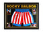 Framed Rocky Balboa boxing shorts signed by Sylvester Stallone, displayed with four film photos.