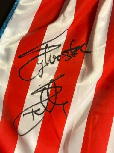 Close-up of Sylvester Stallone’s signature on red and white Rocky IV boxing trunks.