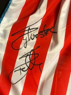 Close-up of Sylvester Stallone’s signature on red and white Rocky IV boxing trunks.