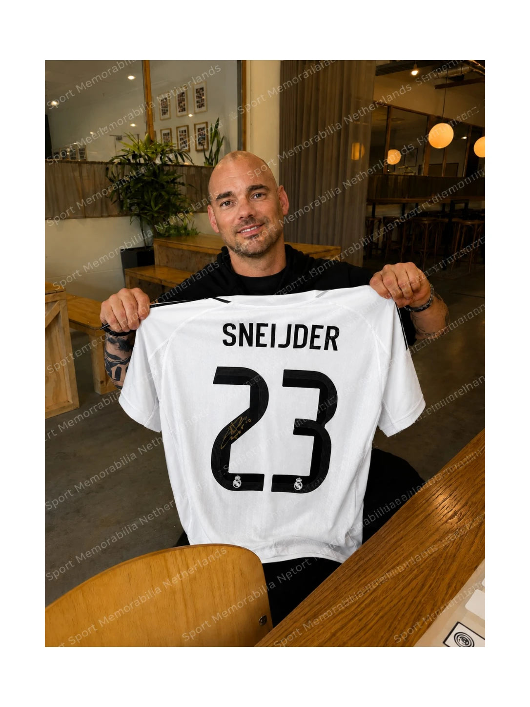 Wesley Sneijder holding a signed Real Madrid football shirt number 23 during a private signing session.