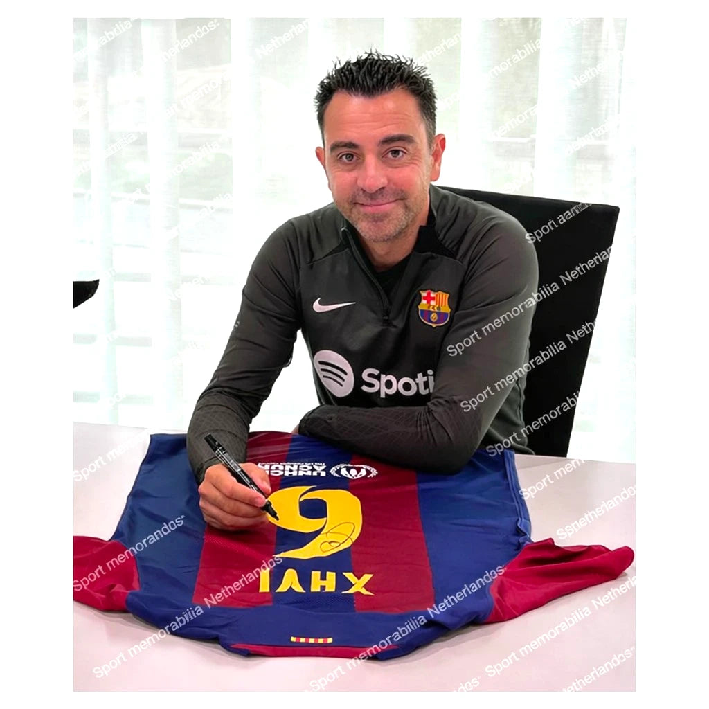Xavi Hernández signeert een FC Barcelona shirt met nummer 6 tijdens een signeersessie.